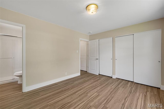 1200 Auber Dr, Manchester, MO 63011 - unfurnished bedroom with light wood-style floors, baseboards, multiple closets, and ensuite bathroom