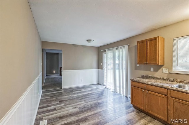 6363 Coventry Dr, Florissant, MO 63033 - kitchen with plenty of natural light, brown cabinets, wood finished floors, a wainscoted wall, and a sink