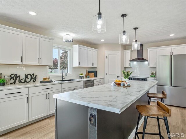 496 E 2nd St, Trenton, IL 62293 - kitchen featuring stainless steel appliances, wall chimney exhaust hood, a sink, a kitchen island, and light wood-style flooring