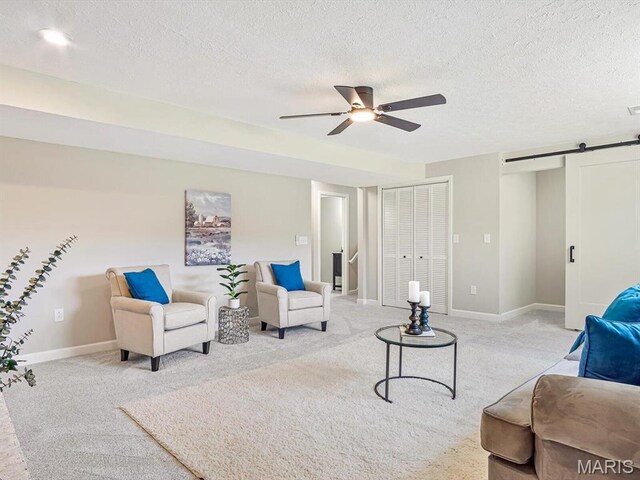 496 E 2nd St, Trenton, IL 62293 - living room featuring light carpet, a barn door, ceiling fan, a textured ceiling, and baseboards