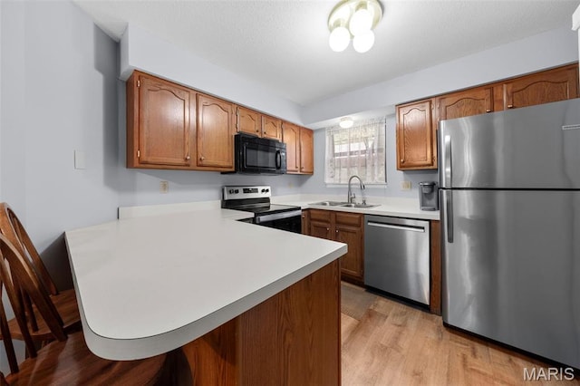 12944 Bryce Canyon Dr, Maryland Heights, MO 63043 - kitchen with stainless steel appliances, a sink, a peninsula, light countertops, and brown cabinetry