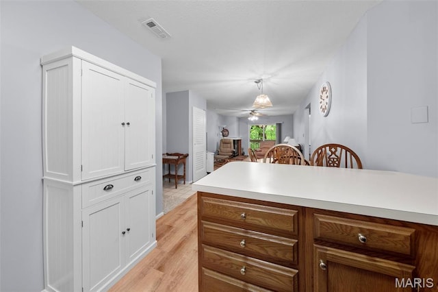12944 Bryce Canyon Dr, Maryland Heights, MO 63043 - kitchen with light countertops, ceiling fan, open floor plan, white cabinetry, and light wood finished floors