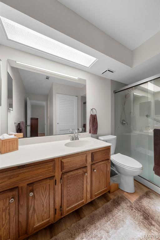 12944 Bryce Canyon Dr, Maryland Heights, MO 63043 - full bathroom featuring wood finished floors, toilet, a stall shower, and vanity