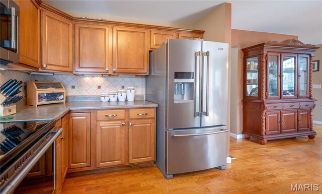 1004 Kodiak Ct, Wentzville, MO 63385 - kitchen featuring stainless steel appliances, light wood-type flooring, decorative backsplash, and brown cabinets
