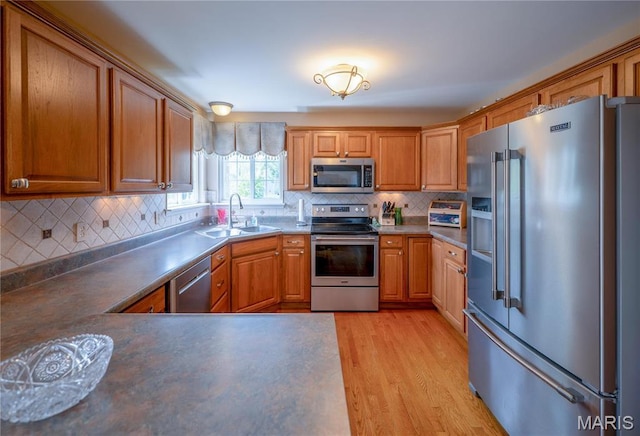 1004 Kodiak Ct, Wentzville, MO 63385 - kitchen featuring appliances with stainless steel finishes, light wood finished floors, tasteful backsplash, and brown cabinets