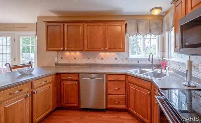 1004 Kodiak Ct, Wentzville, MO 63385 - kitchen featuring appliances with stainless steel finishes, light wood-style floors, brown cabinets, and decorative backsplash