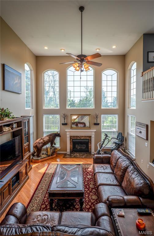 1004 Kodiak Ct, Wentzville, MO 63385 - living room with ceiling fan, light wood-type flooring, a high end fireplace, recessed lighting, and a towering ceiling