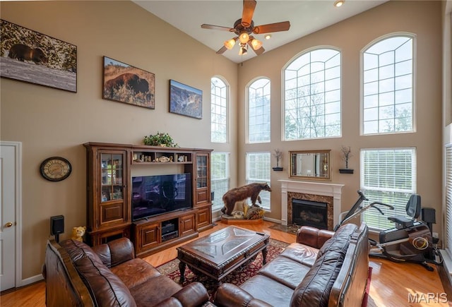 1004 Kodiak Ct, Wentzville, MO 63385 - living room featuring a ceiling fan, a towering ceiling, a high end fireplace, light wood-style flooring, and healthy amount of natural light