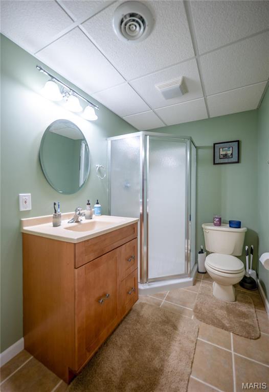 1004 Kodiak Ct, Wentzville, MO 63385 - bathroom featuring a shower stall, vanity, tile patterned flooring, and a paneled ceiling