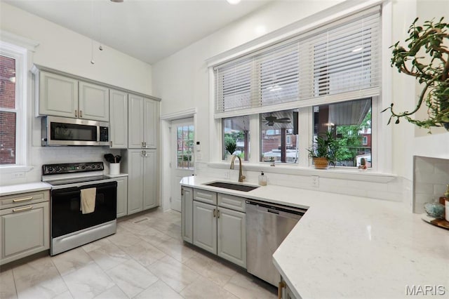 2116 Victor St, Saint Louis, MO 63104 - kitchen featuring appliances with stainless steel finishes, gray cabinets, a sink, backsplash, and light marble finish flooring