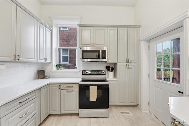 2116 Victor St, Saint Louis, MO 63104 - kitchen with stainless steel microwave, range with electric cooktop, tasteful backsplash, and light countertops