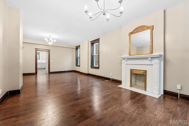 5518 Alaska Ave, Saint Louis, MO 63111 - unfurnished living room with a chandelier, wood finished floors, a brick fireplace, and baseboards