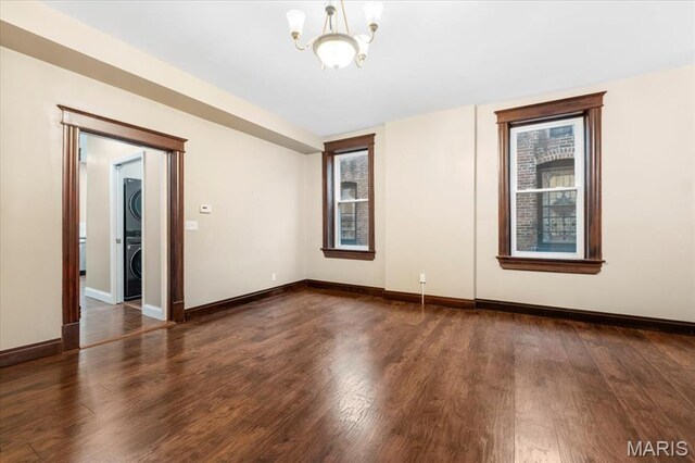 5518 Alaska Ave, Saint Louis, MO 63111 - unfurnished room with stacked washing machine and dryer, a chandelier, wood finished floors, and baseboards
