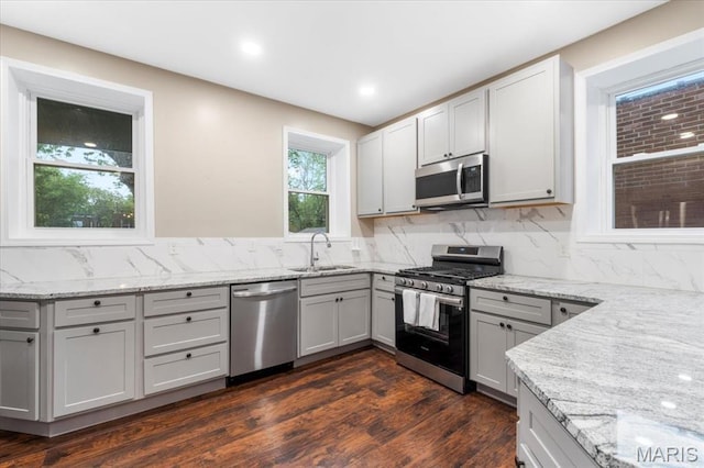 5518 Alaska Ave, Saint Louis, MO 63111 - kitchen with appliances with stainless steel finishes, a sink, dark wood-type flooring, light stone counters, and tasteful backsplash
