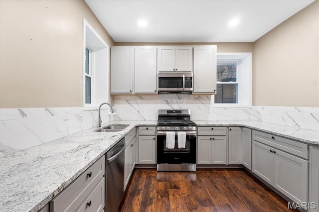 5518 Alaska Ave, Saint Louis, MO 63111 - kitchen featuring stainless steel appliances, a sink, light stone countertops, dark wood-style flooring, and decorative backsplash