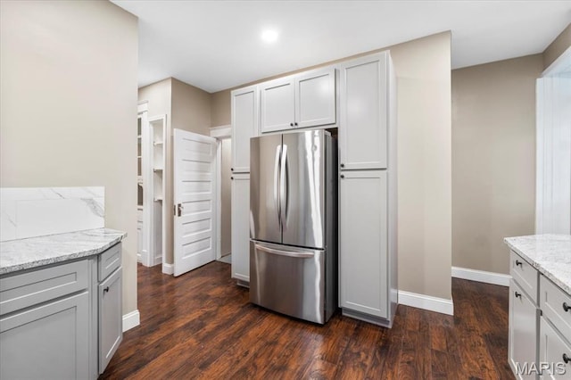 5518 Alaska Ave, Saint Louis, MO 63111 - kitchen featuring freestanding refrigerator, light stone countertops, dark wood-style floors, and baseboards