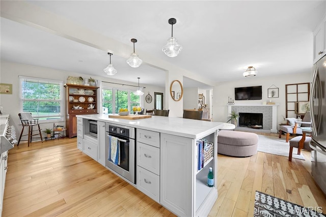 3066 W Meyer Rd, Foristell, MO 63348 - kitchen featuring stainless steel appliances, open shelves, light wood-style flooring, a fireplace, and light countertops