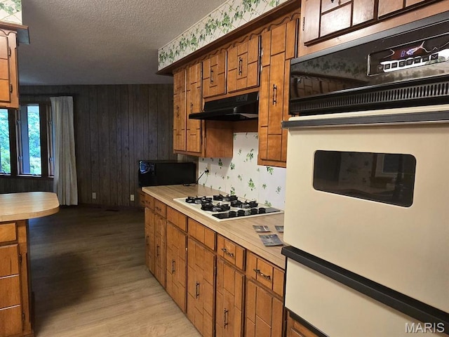16043 County Road 624, Dexter, MO 63841 - kitchen with white appliances, under cabinet range hood, light countertops, brown cabinetry, and a warming drawer