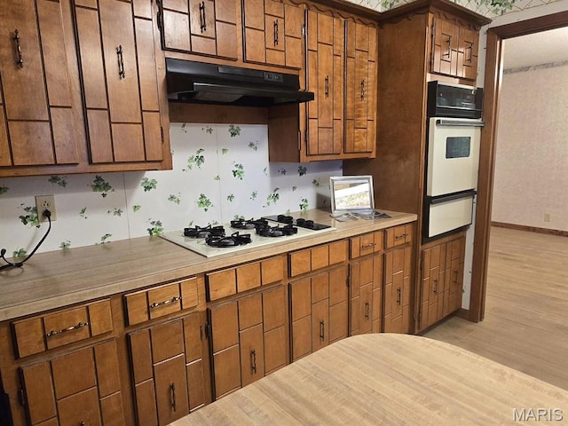16043 County Road 624, Dexter, MO 63841 - kitchen with white appliances, a warming drawer, under cabinet range hood, and brown cabinetry
