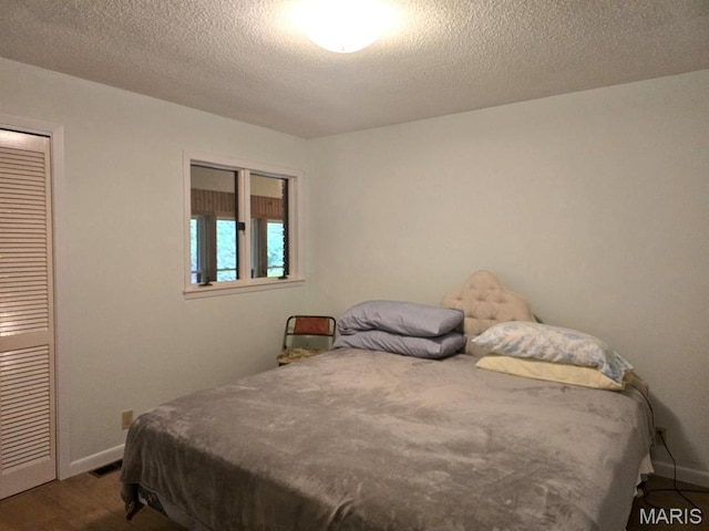 16043 County Road 624, Dexter, MO 63841 - bedroom featuring baseboards, a closet, a textured ceiling, and dark wood-style flooring