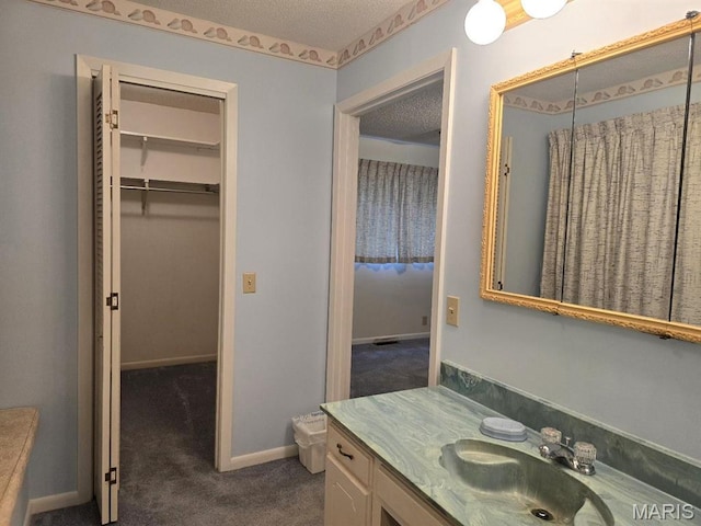 16043 County Road 624, Dexter, MO 63841 - bathroom with vanity, a walk in closet, and a textured ceiling