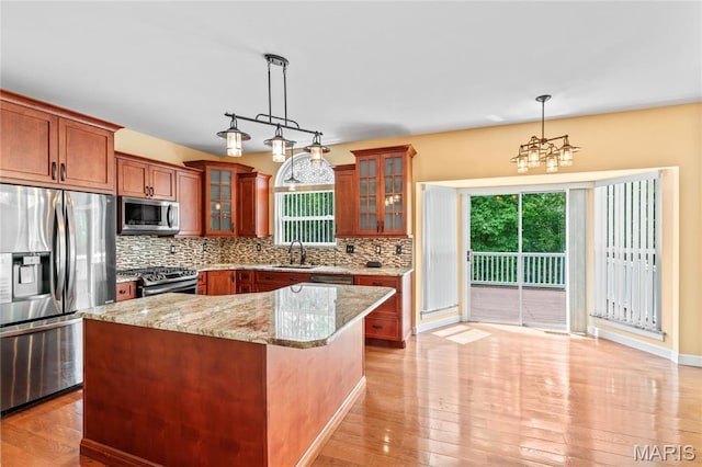2158 Avalon Ridge Cir, Fenton, MO 63026 - kitchen featuring stainless steel appliances, tasteful backsplash, light stone counters, pendant lighting, and a sink