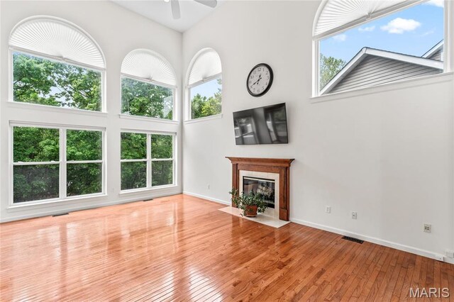 2158 Avalon Ridge Cir, Fenton, MO 63026 - unfurnished living room featuring ceiling fan, plenty of natural light, a fireplace with flush hearth, and a towering ceiling