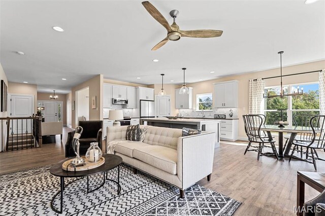 living area with a chandelier, light wood-style flooring, ceiling fan, recessed lighting, and baseboards