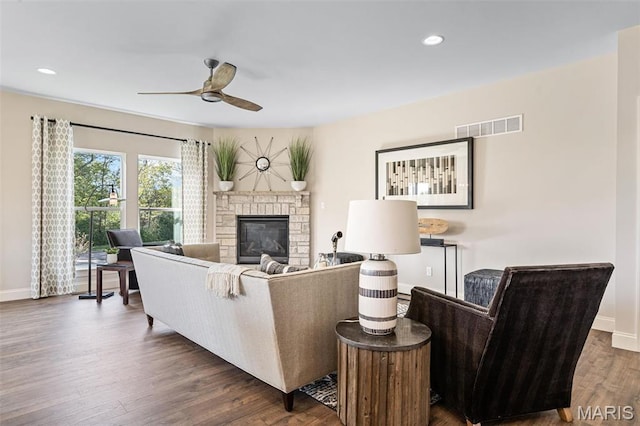 living room featuring ceiling fan, baseboards, a stone fireplace, dark wood finished floors, and recessed lighting