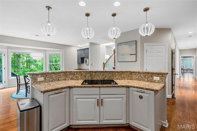 1424 Haarman Oak Dr, Wildwood, MO 63005 - kitchen featuring black electric stovetop, plenty of natural light, wood finished floors, a kitchen island with sink, and recessed lighting