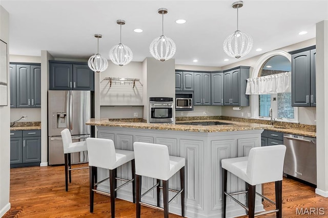 1424 Haarman Oak Dr, Wildwood, MO 63005 - kitchen featuring appliances with stainless steel finishes, gray cabinetry, light stone counters, dark wood finished floors, and recessed lighting
