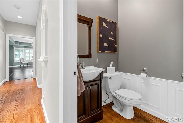 1424 Haarman Oak Dr, Wildwood, MO 63005 - bathroom featuring wood finished floors, toilet, wainscoting, vanity, and a decorative wall