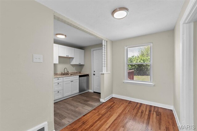 4717 Roxie St, Saint Louis, MO 63121 - kitchen featuring a sink, dishwasher, baseboards, wood finished floors, and white cabinets