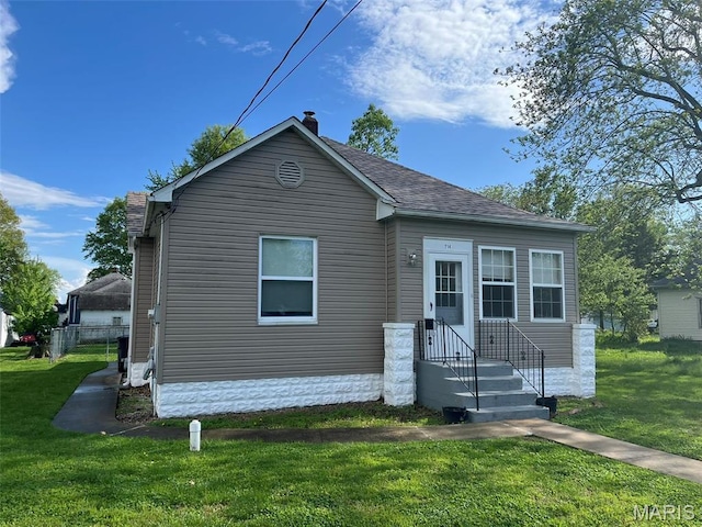 view of front of property featuring a front yard, a chimney, and roof with shingles