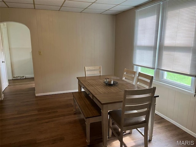 dining room featuring wood finished floors, baseboards, and arched walkways