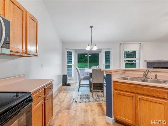 927 Annabrook Park Dr, Ofallon, MO 63366 - kitchen featuring a sink, stainless steel microwave, light wood-style floors, hanging light fixtures, and light countertops