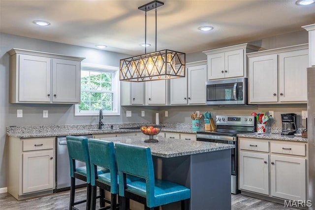 1541 Fairfield Dr, Lebanon, MO 65536 - kitchen featuring appliances with stainless steel finishes, a sink, wood finished floors, a breakfast bar area, and recessed lighting