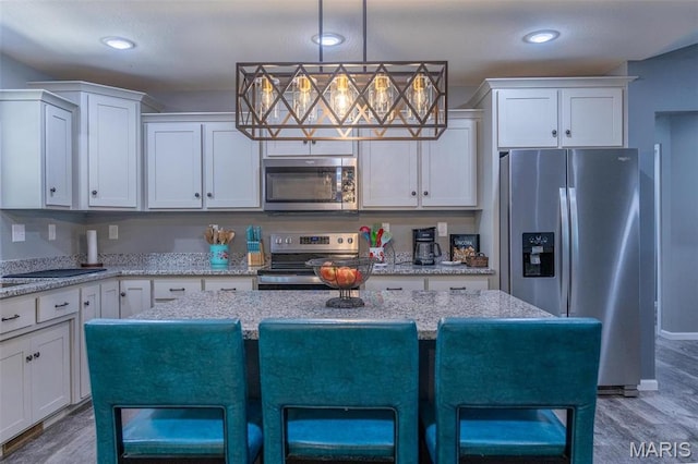 1541 Fairfield Dr, Lebanon, MO 65536 - kitchen with stainless steel appliances, wood finished floors, white cabinets, a kitchen breakfast bar, and a center island