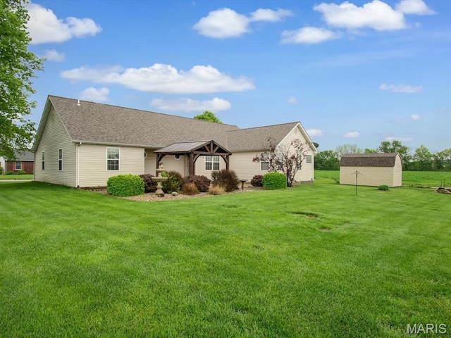 ranch-style house with a gazebo, a storage unit, an outbuilding, a front yard, and a shingled roof
