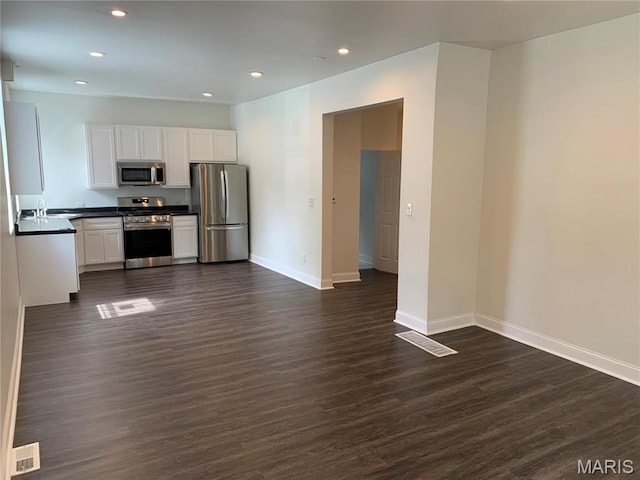 3616 Osceola St, Saint Louis, MO 63116 - kitchen with stainless steel appliances, dark countertops, dark wood finished floors, baseboards, and white cabinetry