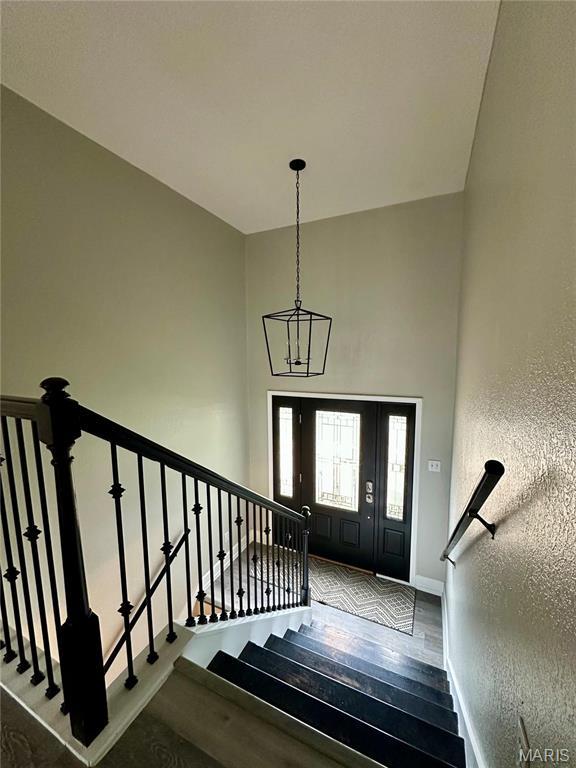 1324 Chelsea Ln, Rolla, MO 65401 - entryway with baseboards, wood finished floors, a chandelier, a textured wall, and stairway