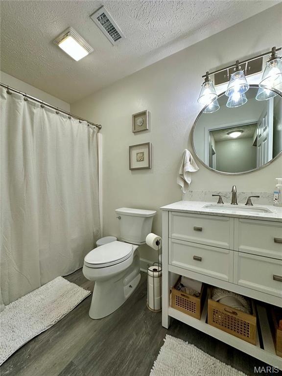 1324 Chelsea Ln, Rolla, MO 65401 - bathroom featuring wood finished floors, toilet, a textured ceiling, vanity, and curtained shower