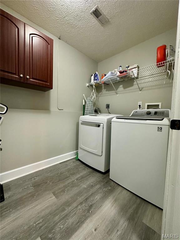 1324 Chelsea Ln, Rolla, MO 65401 - washroom with baseboards, separate washer and dryer, dark wood-type flooring, cabinet space, and a textured ceiling