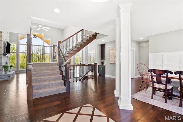 stairway with wood-type flooring, ceiling fan, decorative columns, a fireplace, and recessed lighting