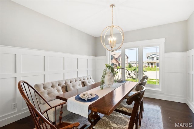 dining area with a decorative wall, a chandelier, dark wood finished floors, and a wainscoted wall