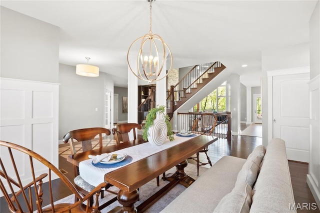 dining area featuring wood finished floors, stairway, a chandelier, and baseboards