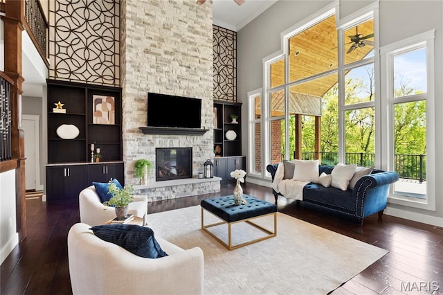living area featuring plenty of natural light, ceiling fan, hardwood / wood-style floors, a towering ceiling, and ornamental molding