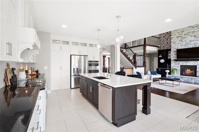 kitchen featuring appliances with stainless steel finishes, a sink, a breakfast bar area, glass insert cabinets, and open floor plan