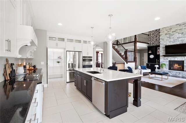 kitchen featuring stainless steel appliances, a sink, a kitchen bar, glass insert cabinets, and open floor plan