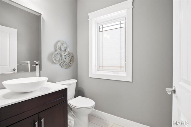 half bathroom featuring toilet, vanity, and baseboards
